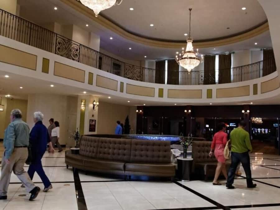 A spacious lobby with a grand chandelier, a round seating area, and a second-floor balcony.