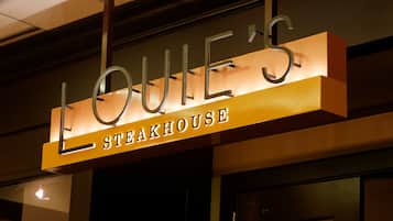 Letrero de 'LOUIE'S STEAKHOUSE' con diseño moderno y letras iluminadas.
