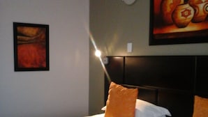 A hotel room with a large bed, a headboard, and a painting on the wall.