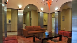 A lobby with a sofa, a coffee table, and a vase. There are arches and a chandelier.