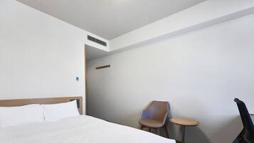A hotel room with a large bed, a chair, a small table, and a desk.