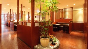 A restaurant interior with wooden floors, a central plant, and a seating area with tables and chairs. - Daiwa Roynet Hotel Hakata - Gion (Fukuoka)