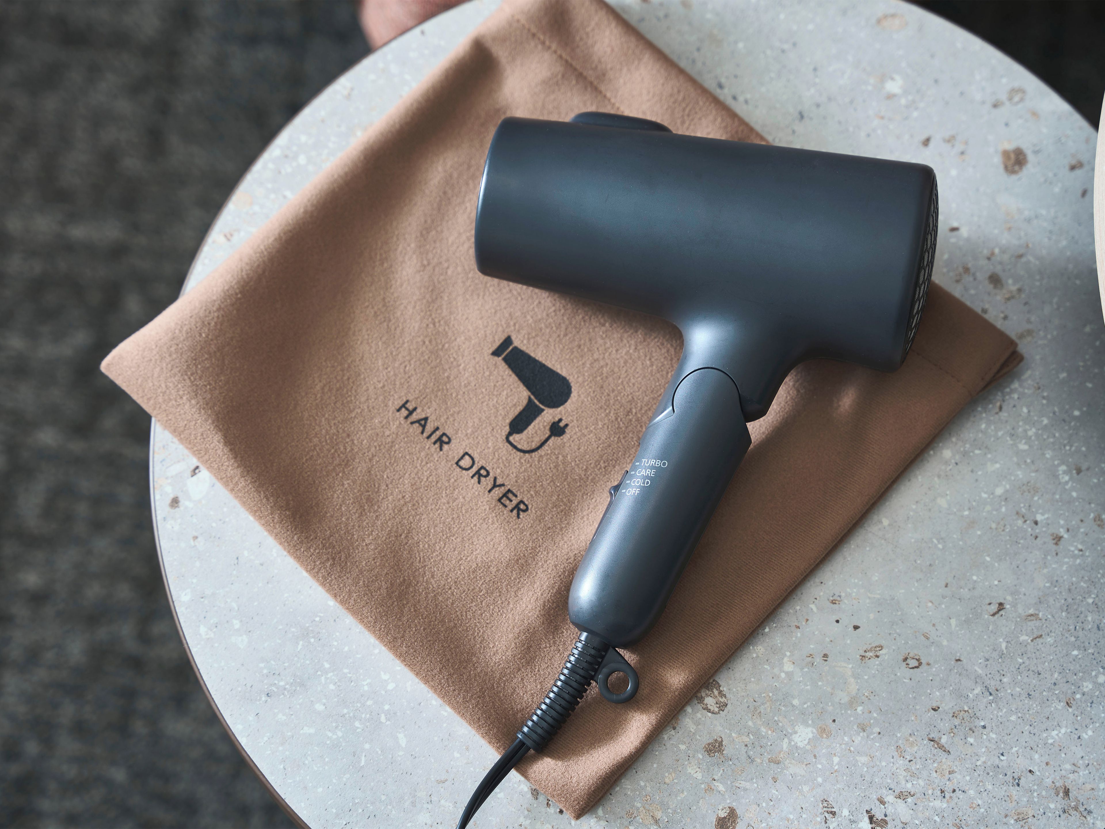 A hair dryer on a beige cloth with the text 'HAIR DRYER' and a logo.