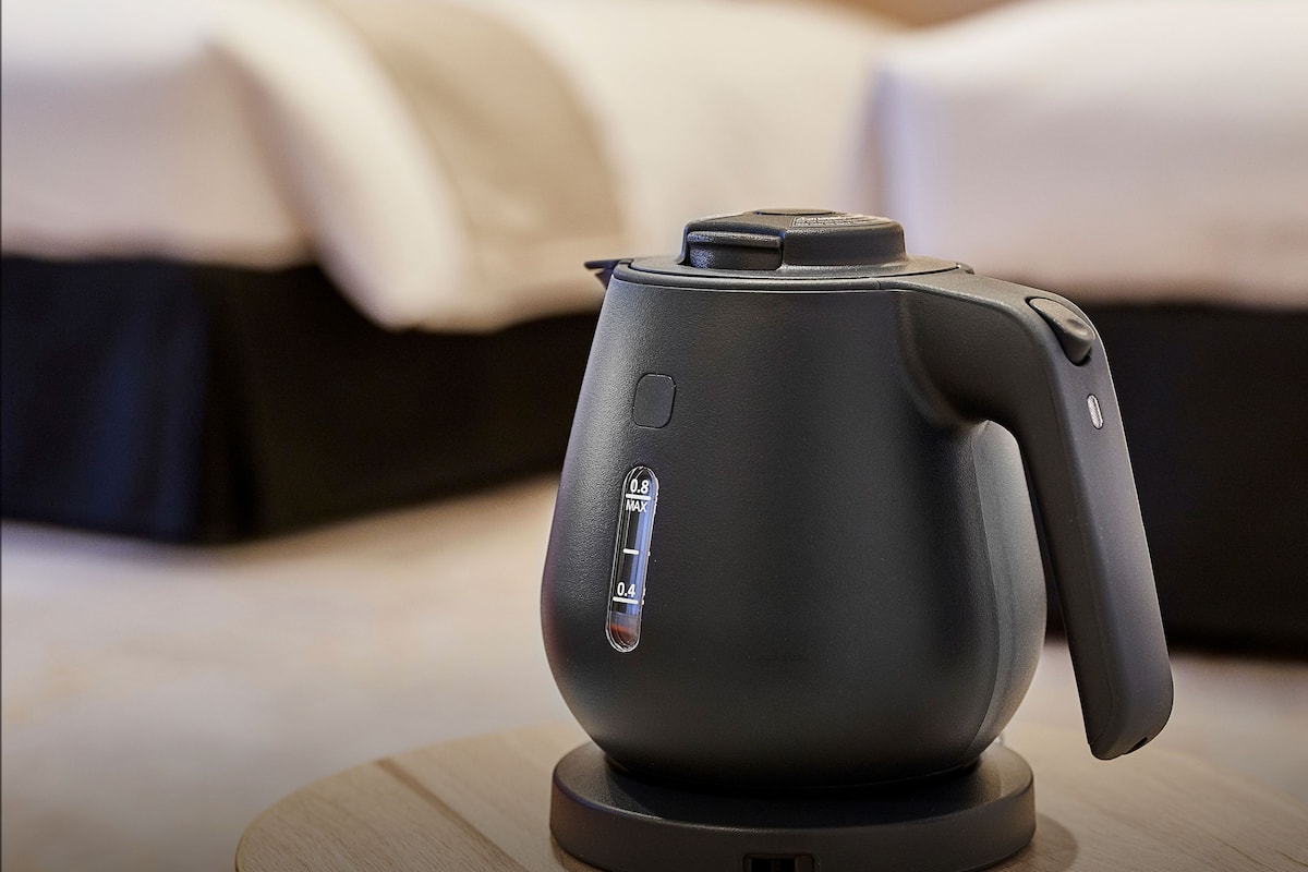 A modern electric kettle on a wooden table in a hotel room.