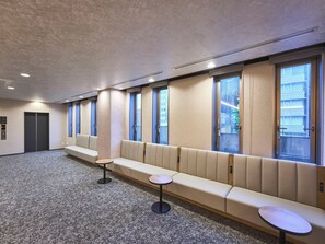 Un vestíbulo de hotel con un largo banco, una mesa pequeña y un mostrador de recepción.