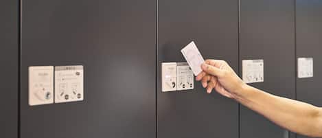 A hand holding a card in front of a set of lockers with instructions and symbols on them.