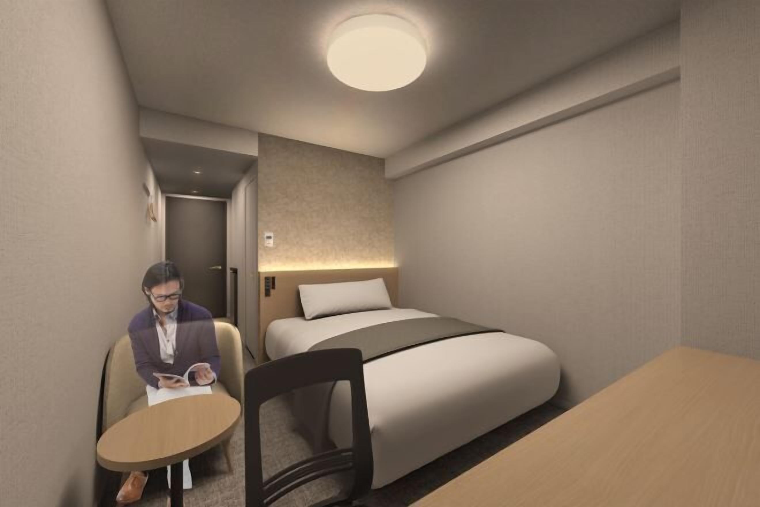 Hotellihuone, jossa on sänky, työpöytä ja tuoli.