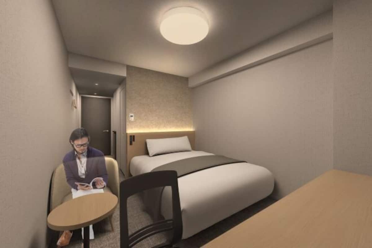 Hotellihuone, jossa on sänky, työpöytä ja tuoli.
