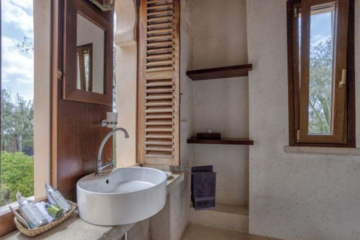 A bathroom with a white sink, wooden door, and a window.