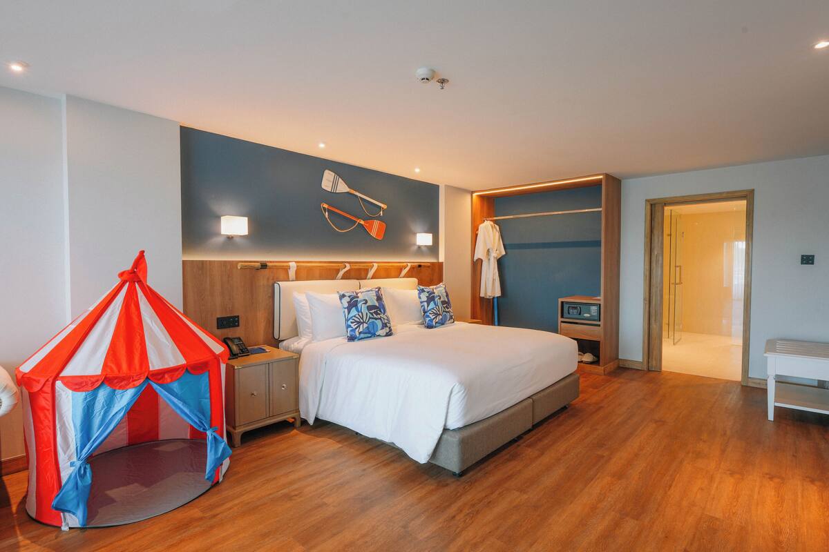 Een slaapkamer met een bed, nachtkastje, lamp en een klein tentachtig constructie.