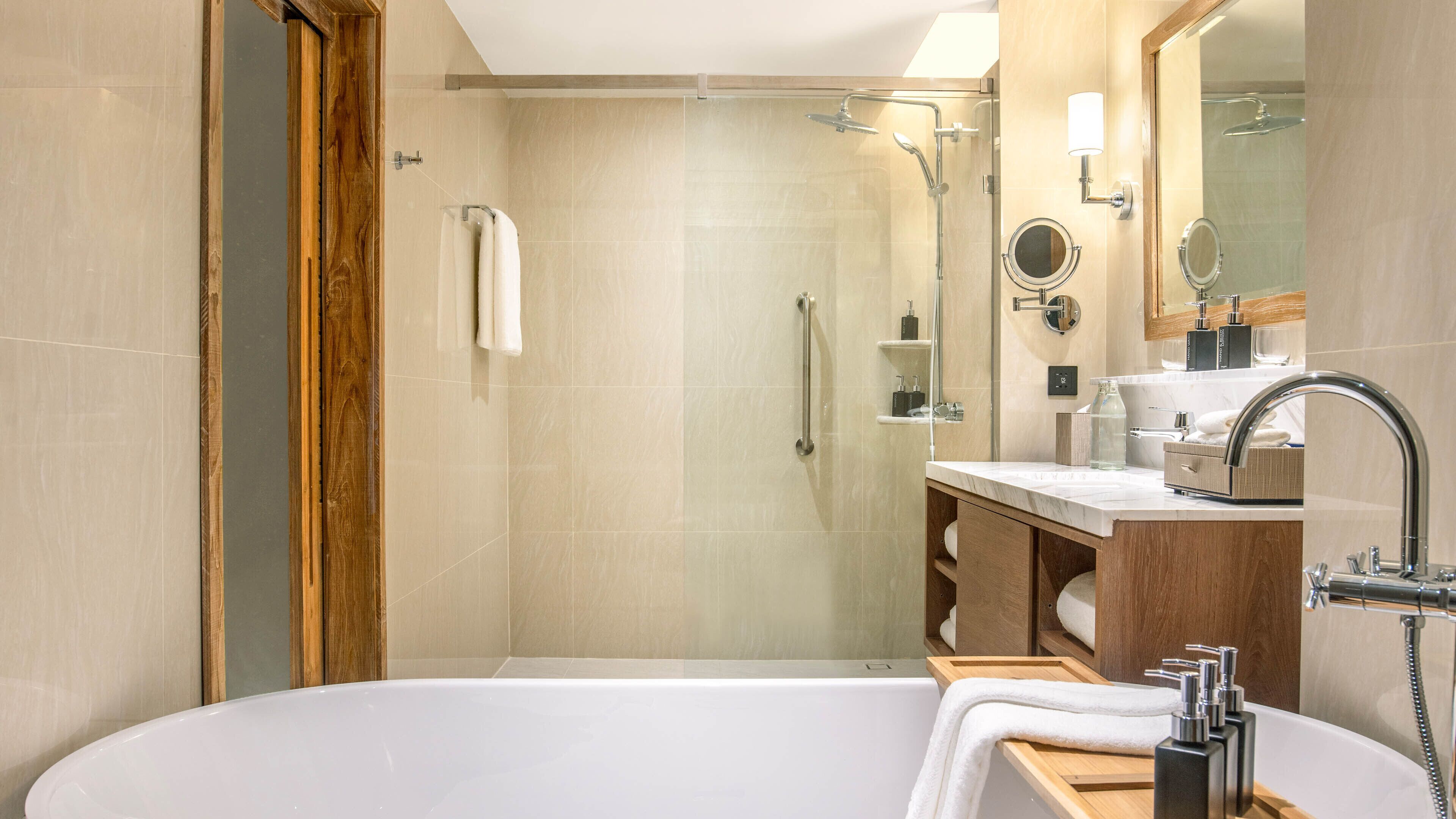 A modern bathroom with a glass-enclosed shower, a freestanding bathtub, and a vanity with a mirror.