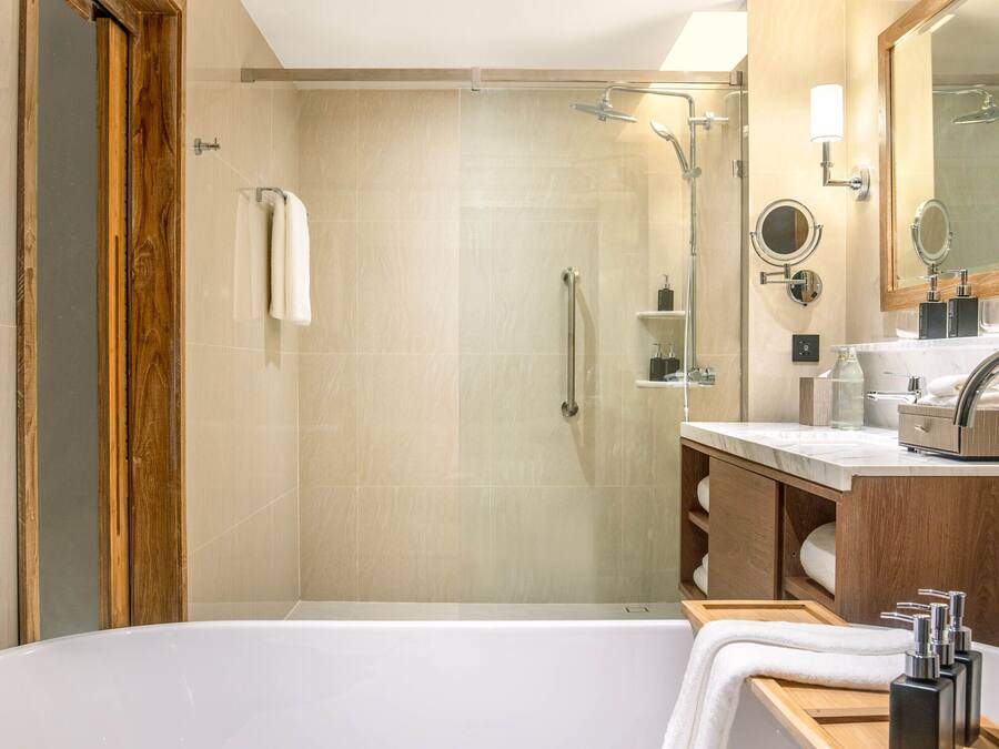 A modern bathroom with a glass-enclosed shower, a freestanding bathtub, and a vanity with a mirror.
