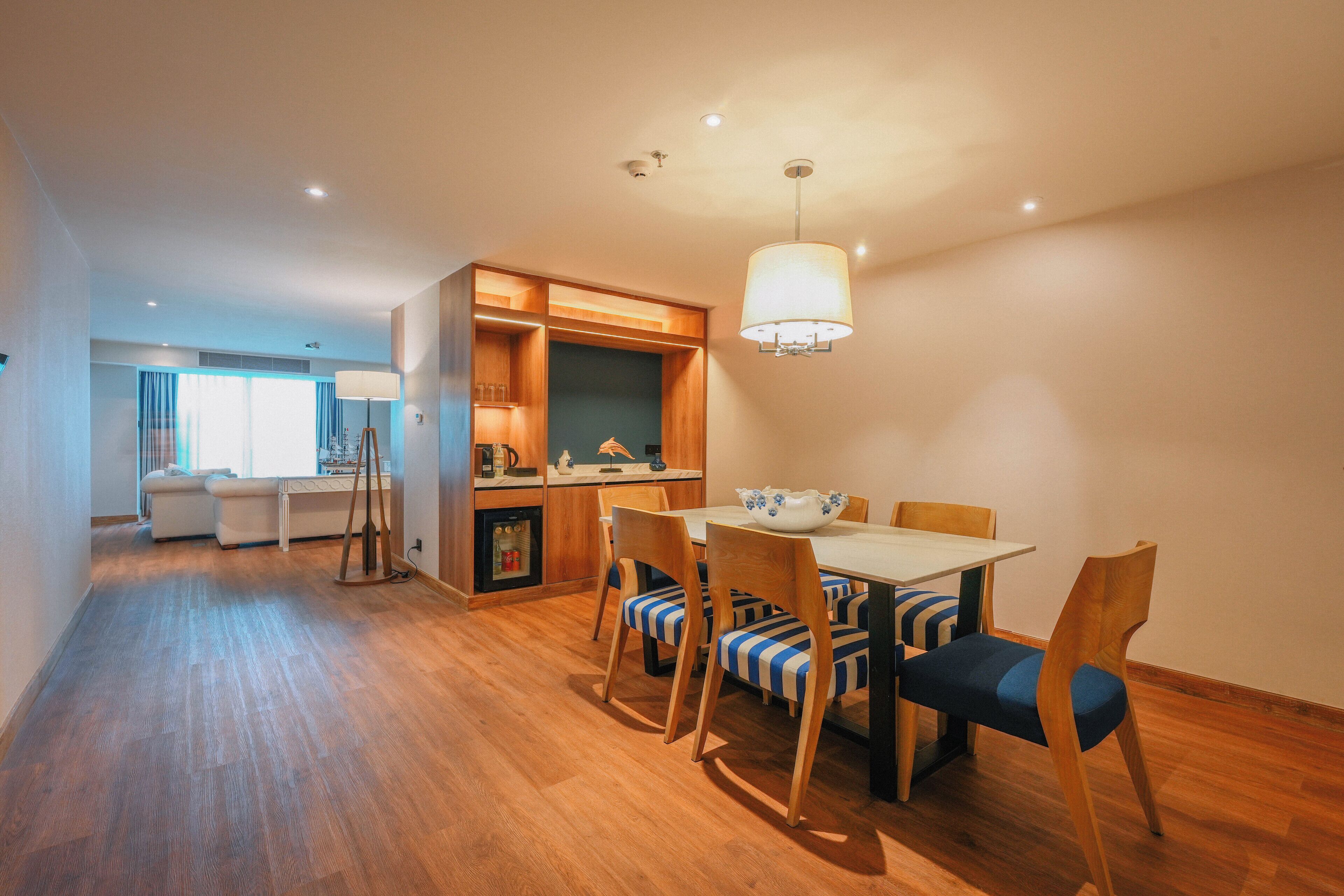Una cocina moderna con armarios de madera, una mesa de comedor con sillas a rayas y una lámpara colgante.