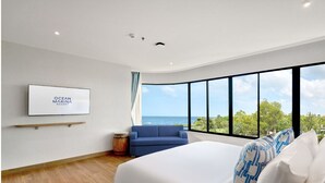 Een moderne slaapkamer met een groot bed, een blauwe bank en uitzicht op zee.