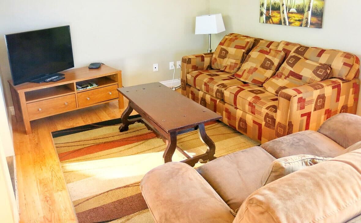 A living room with a sofa, a coffee table, a TV, and a lamp.