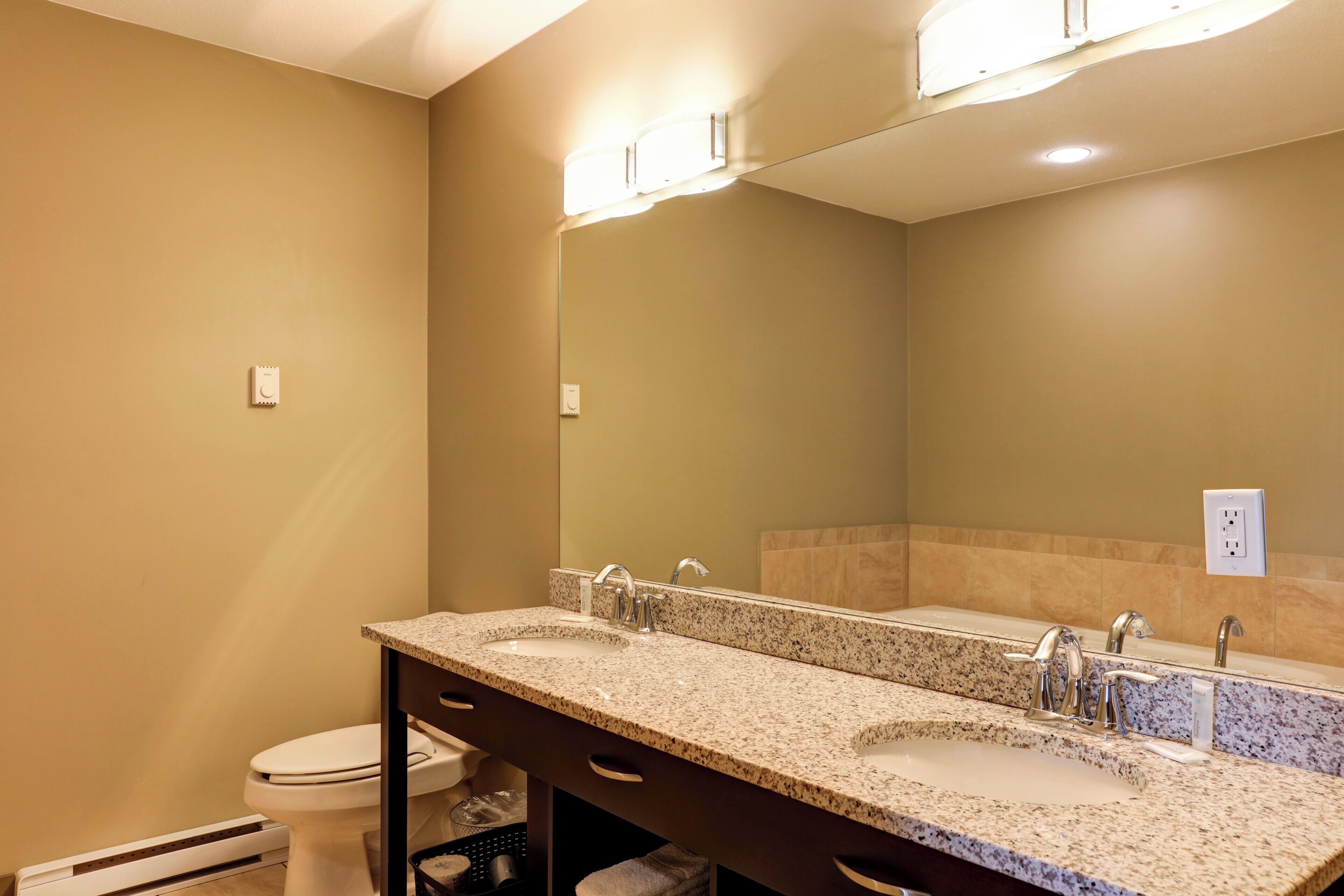 Une salle de bain avec deux lavabos, des toilettes et un grand miroir.