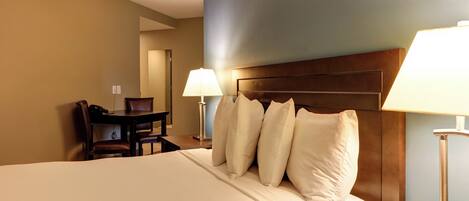 Una habitación de hotel con una cama grande, un escritorio con una silla y dos lámparas de noche.