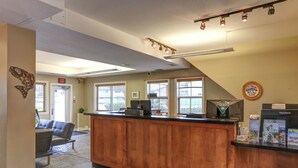A reception area with a wooden counter, a reception desk, a chair, and a wall-mounted sign.