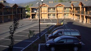 A building with multiple wooden balconies, a parking lot, and mountains in the background.