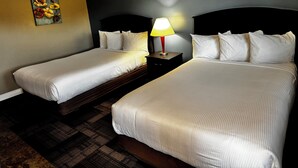 A hotel room with two beds, a nightstand with a lamp, and a painting on the wall.