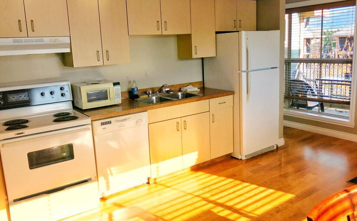 Une cuisine avec des meubles de rangement en bois, un four à micro-ondes, une cuisinière, un évier et un réfrigérateur.