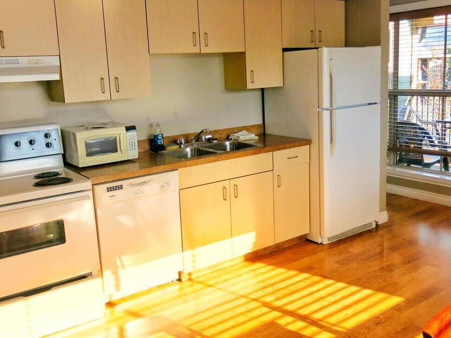 Une cuisine avec des meubles de rangement en bois, un four à micro-ondes, une cuisinière, un évier et un réfrigérateur.