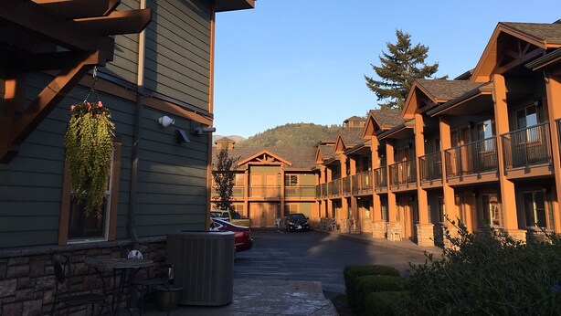 A row of wooden buildings with balconies, a clear sky, and a mountain in the background.
