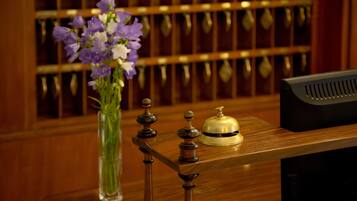 Una reception con un vaso di fiori viola, una campana e un monitor nero.