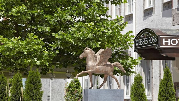 A statue of a winged horse in front of a building with a sign that reads "WEISS ROSS HOTEL".
