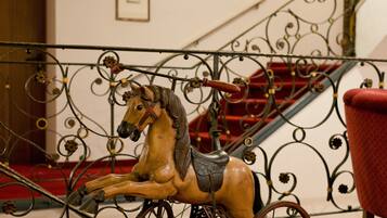 Un caballo de carrusel con silla de montar y riendas, montado sobre un soporte metálico con detalles decorativos.