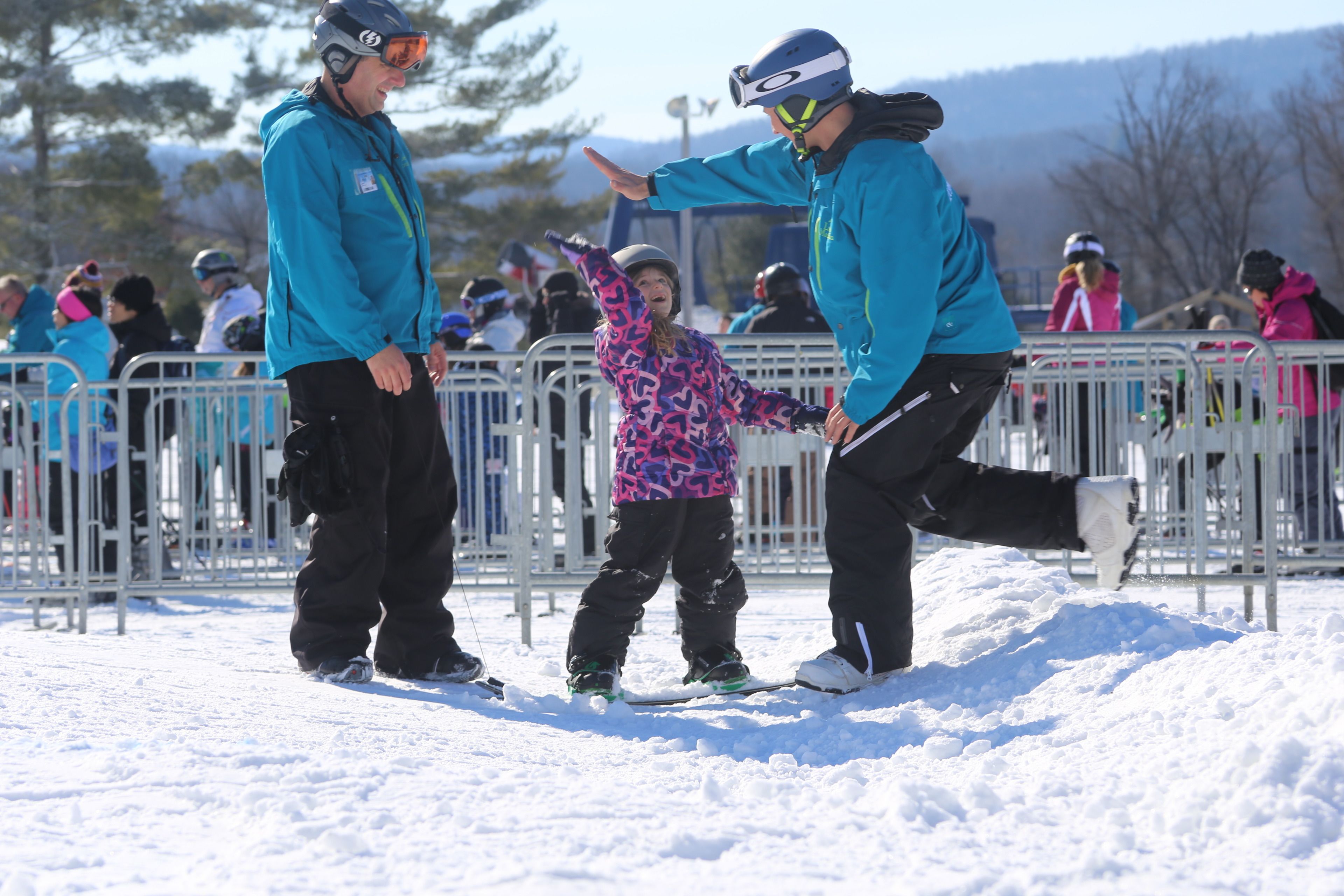 Een besneeuwde buitenruimte met metalen hekken en mensen in winterkleding.