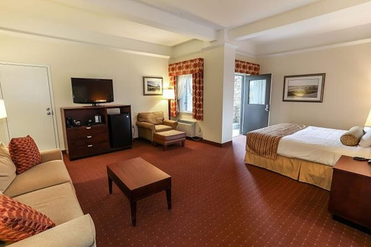 A hotel room with a bed, a sofa, a TV, a desk, and a chair.
