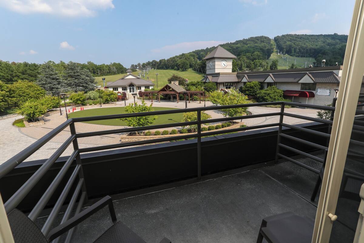 A balcony with a view of a park, buildings, and a clock tower.