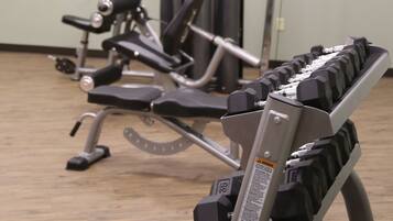 Uma academia com diversos equipamentos de exercício, incluindo um banco de supino e uma máquina de polia.