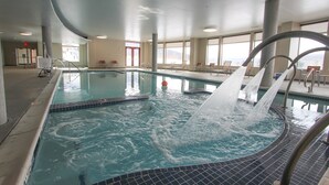 Ein Hallenbad mit Wasserspiel, Sitzgelegenheit und großen Fenstern.