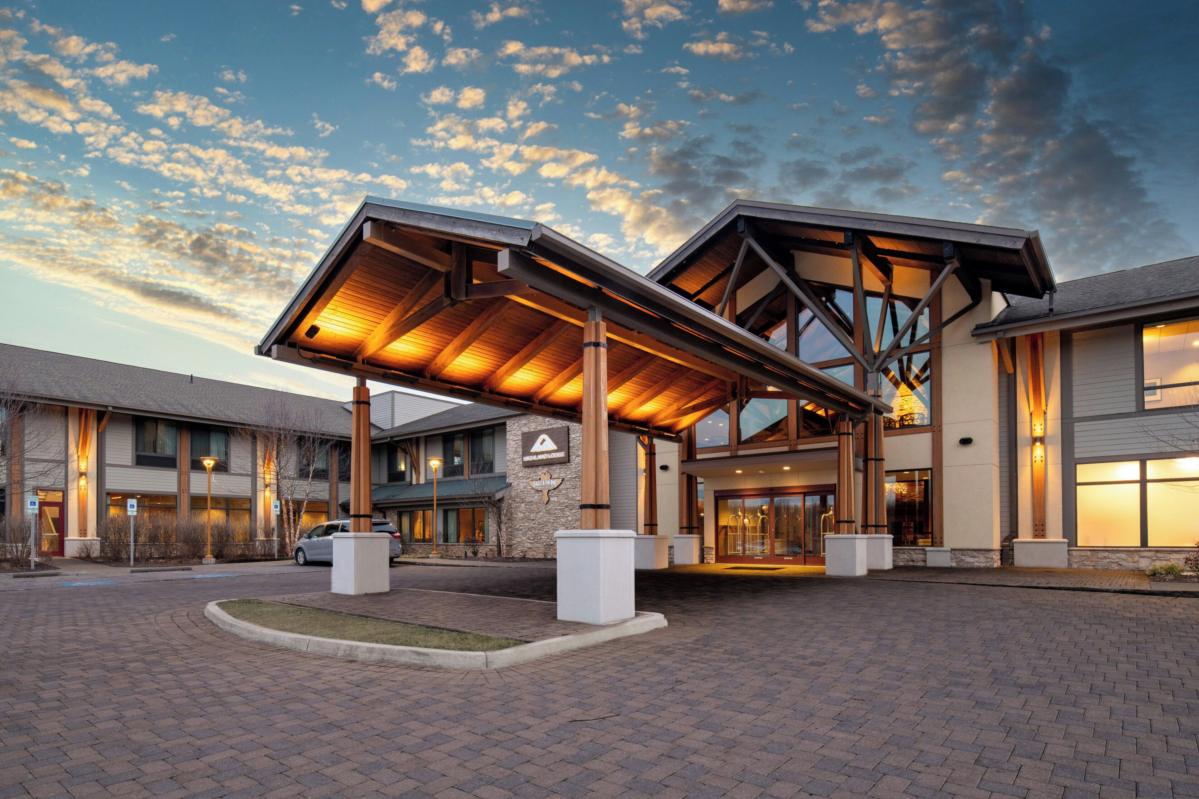 A hotel entrance with a covered walkway, stone pillars, and a clear sky.
