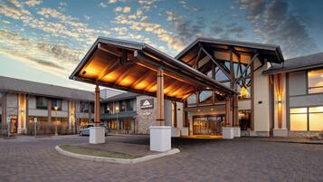 A hotel entrance with a covered walkway, stone pillars, and a clear sky.