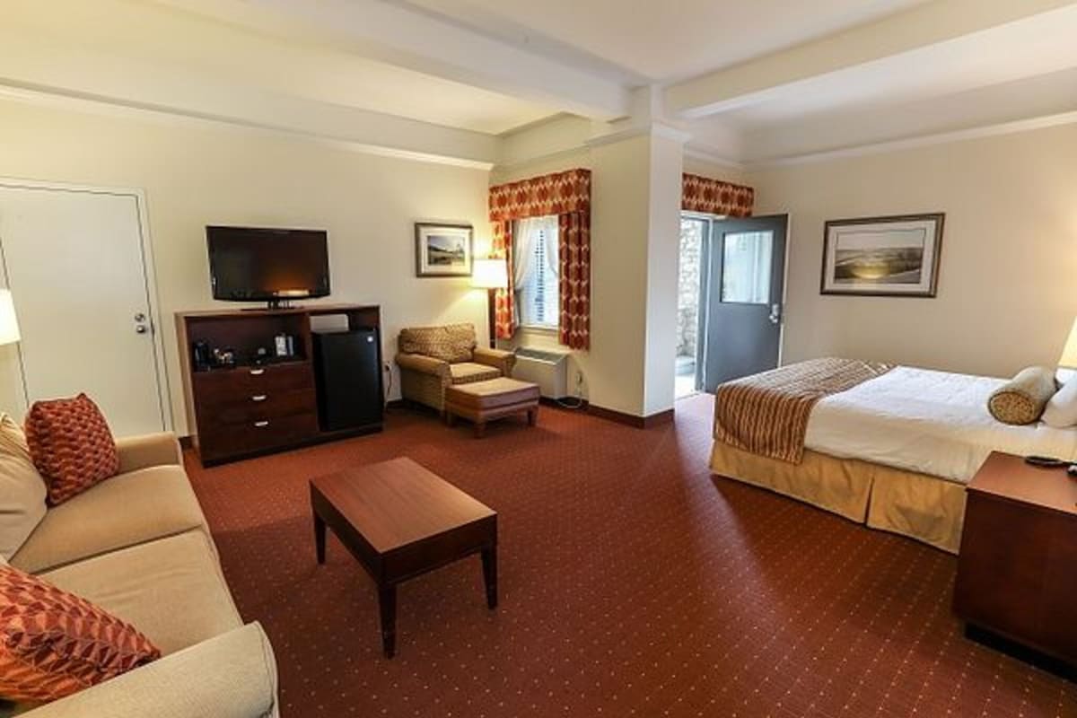 A hotel room with a bed, a sofa, a TV, a desk, and a chair.