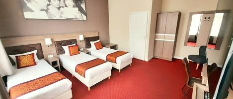 A hotel room with two beds, a wardrobe, a mirror, and a television.