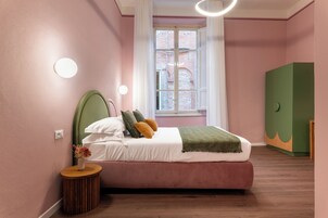 Una camera da letto con un letto, una finestra, un'armadio verde e un comodino con un vaso di fiori.