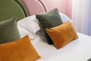 Un letto con quattro cuscini nei colori verde, bianco e senape.