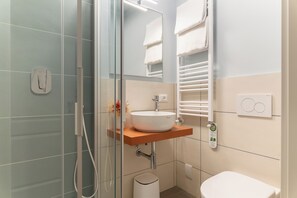 A modern bathroom with a glass shower enclosure, a white sink with a wooden countertop, and a white toilet. - Piccolo Hotel Puccini  (Lucca)