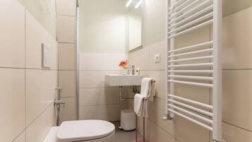 Un baño moderno con inodoro, lavamanos y toallero.