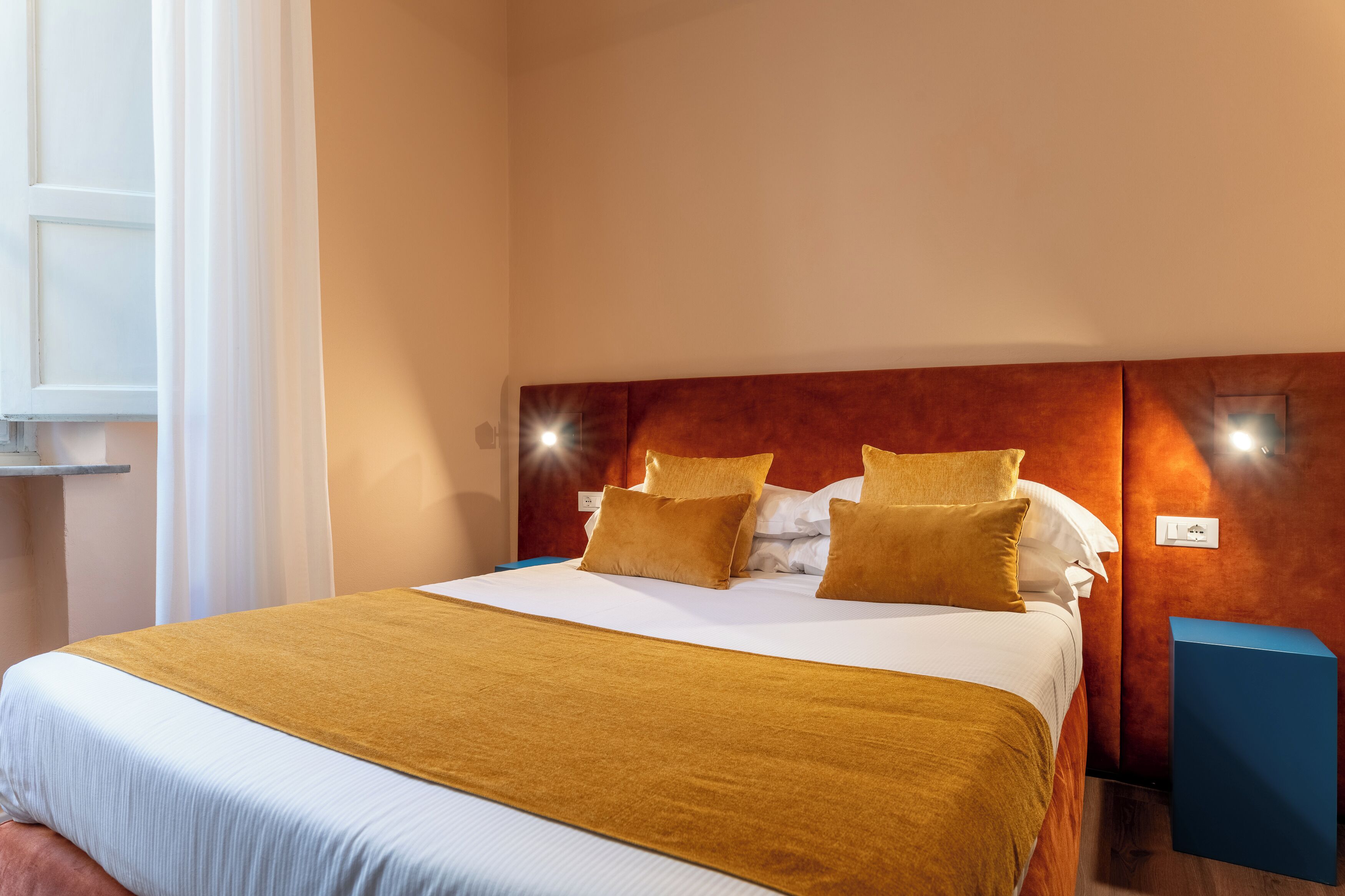 Una camera d'albergo con un letto grande, una testiera in legno e due comodini.