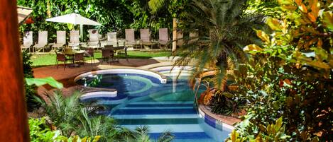 Una piscina de diseño curvo rodeada de exuberante vegetación y palmeras.