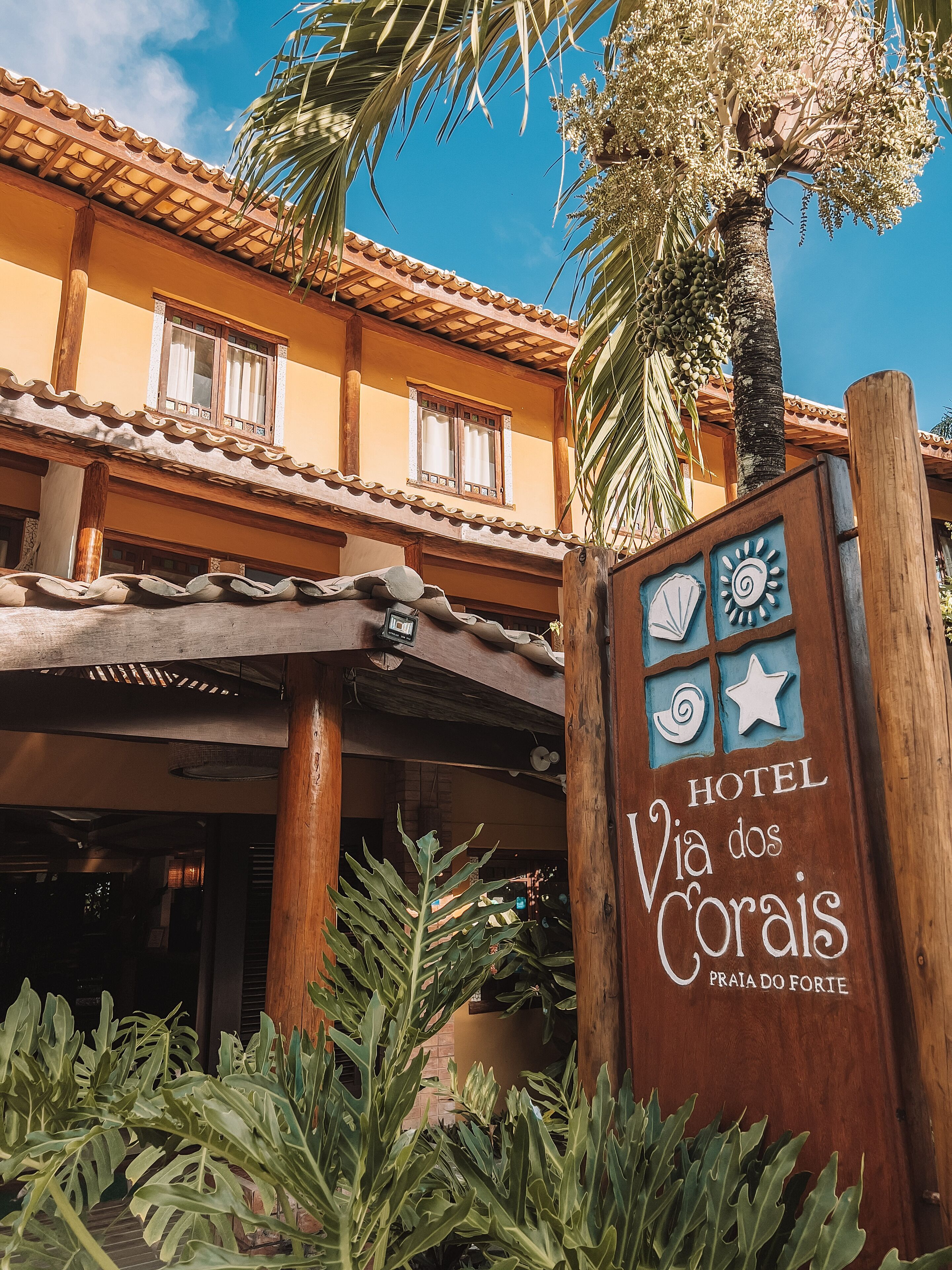 A hotel entrance with a sign reading "HOTEL Via dos Corais Praia do Forte."