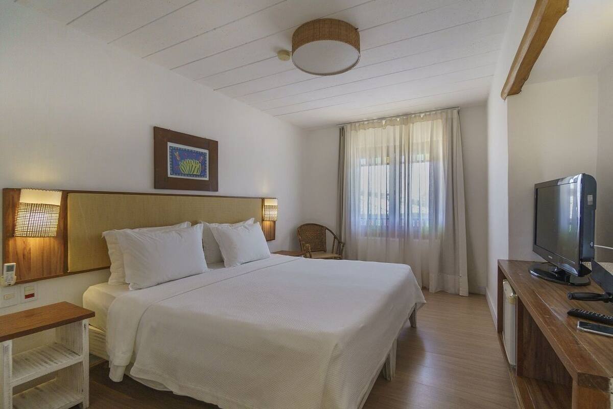 Une chambre d’hôtel avec un grand lit, une télévision, un bureau et une chaise.