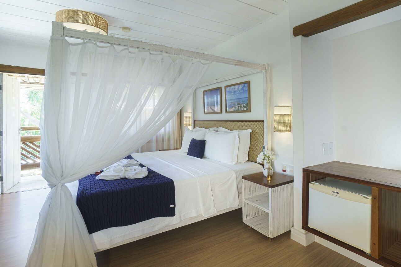 Un dormitorio con cama a dosel, una mesita de noche con lámpara y un mueble auxiliar pequeño.