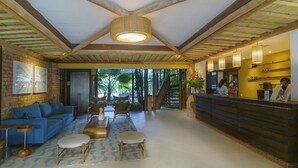Un hall d’entrée spacieux avec un canapé bleu, une table basse en bois et un comptoir d’accueil.