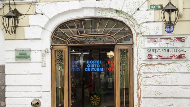 A hotel entrance with a glass door, a sign indicating it is a cultural hostel, and a street lamp above. - Hostal Quito Cultural (Quito)